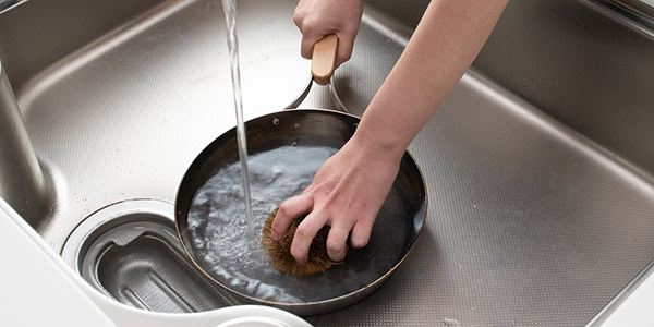 While the ironware is still warm, use a scrub brush or a bamboo whisk and wash it with hot water.
