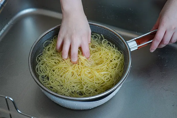 スパゲティが茹で上がったらざるにあけ、氷水でしめる