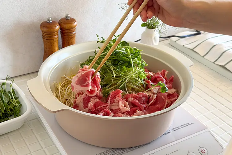 鍋の中心に豆もやしを山高に盛り、その上に豆苗の半量をのせる。周りに牛バラ薄切り肉を敷き詰める。