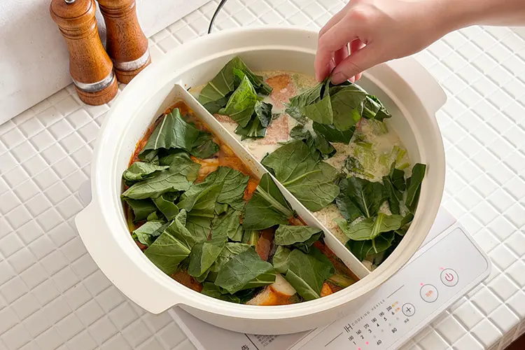 食材がしんなりしたら、それぞれに小松菜の葉を半量ずつ加え、再度蓋をする