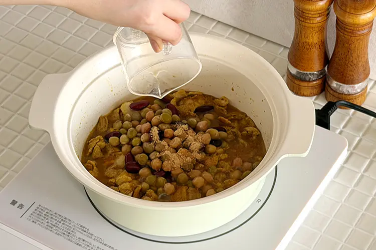 豚バラ肉に火が通ったらミックスビーンズ、【A】を加え、フタをして加熱する。