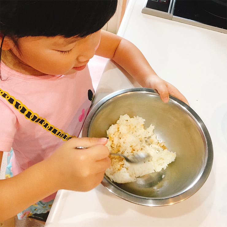ご飯を混ぜるお手伝いをする子ども