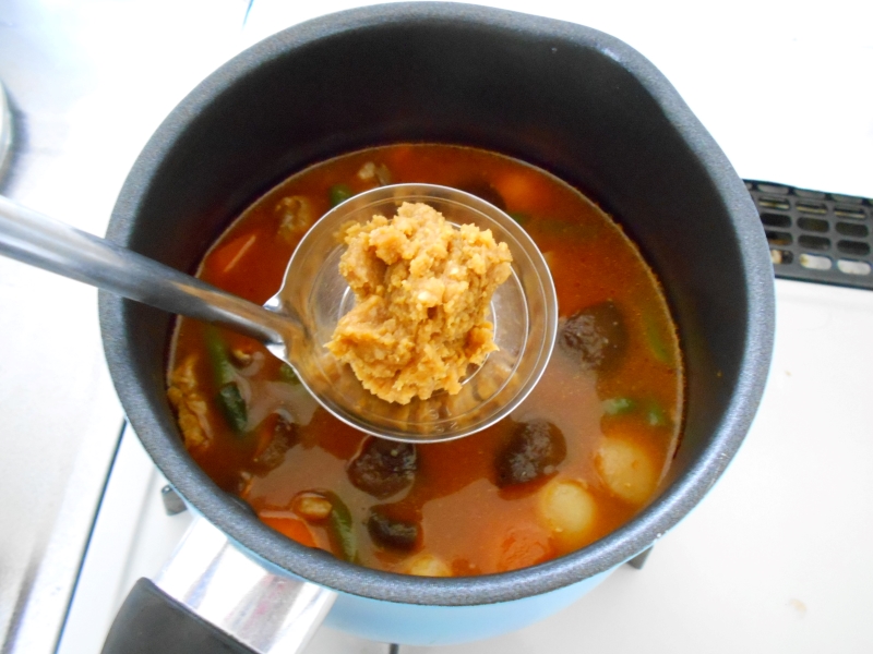 お玉に乗った味噌を溶かすところ