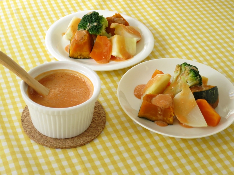 白いココットに入ったドレッシングと、白いお皿に盛り付けられた温野菜の画像