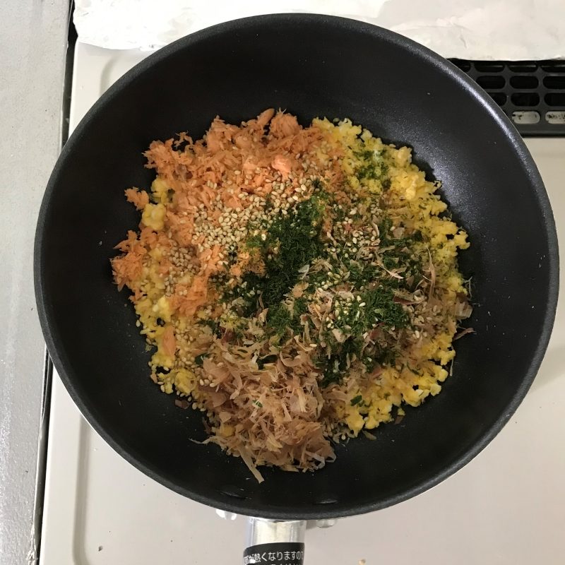 炒ったたまごに鰹節、青のり、ゴマ、サケフレークを入れてさらに炒っていく