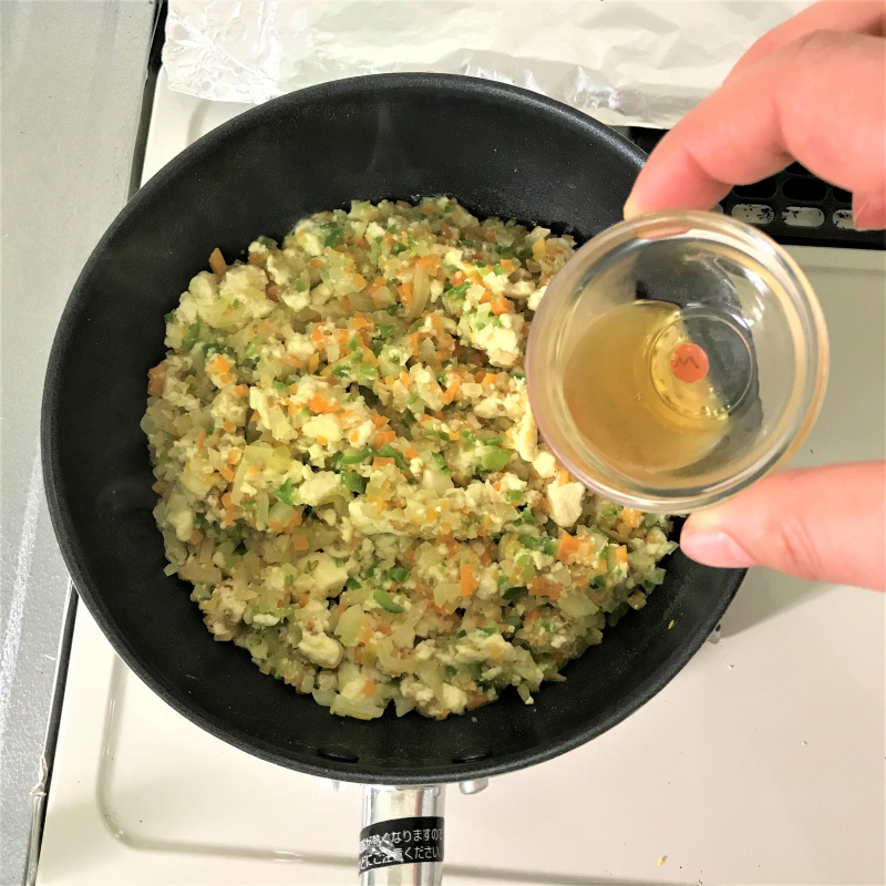 炒めた材料にごま油をかけている画像