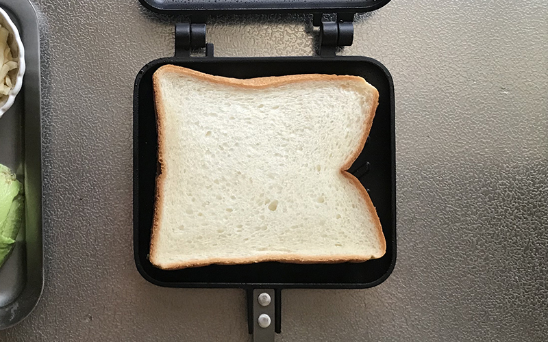 食パンを乗せ、シュレッドチーズ、アボカド、ショルダーベーコンの順に乗せる。