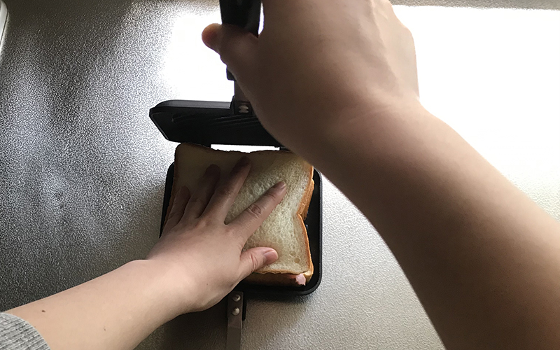 ホットサンドのパンを押さえながらホットサンドメーカーを閉じる