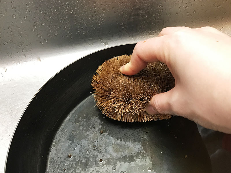 鉄フライパンをたわしで洗う